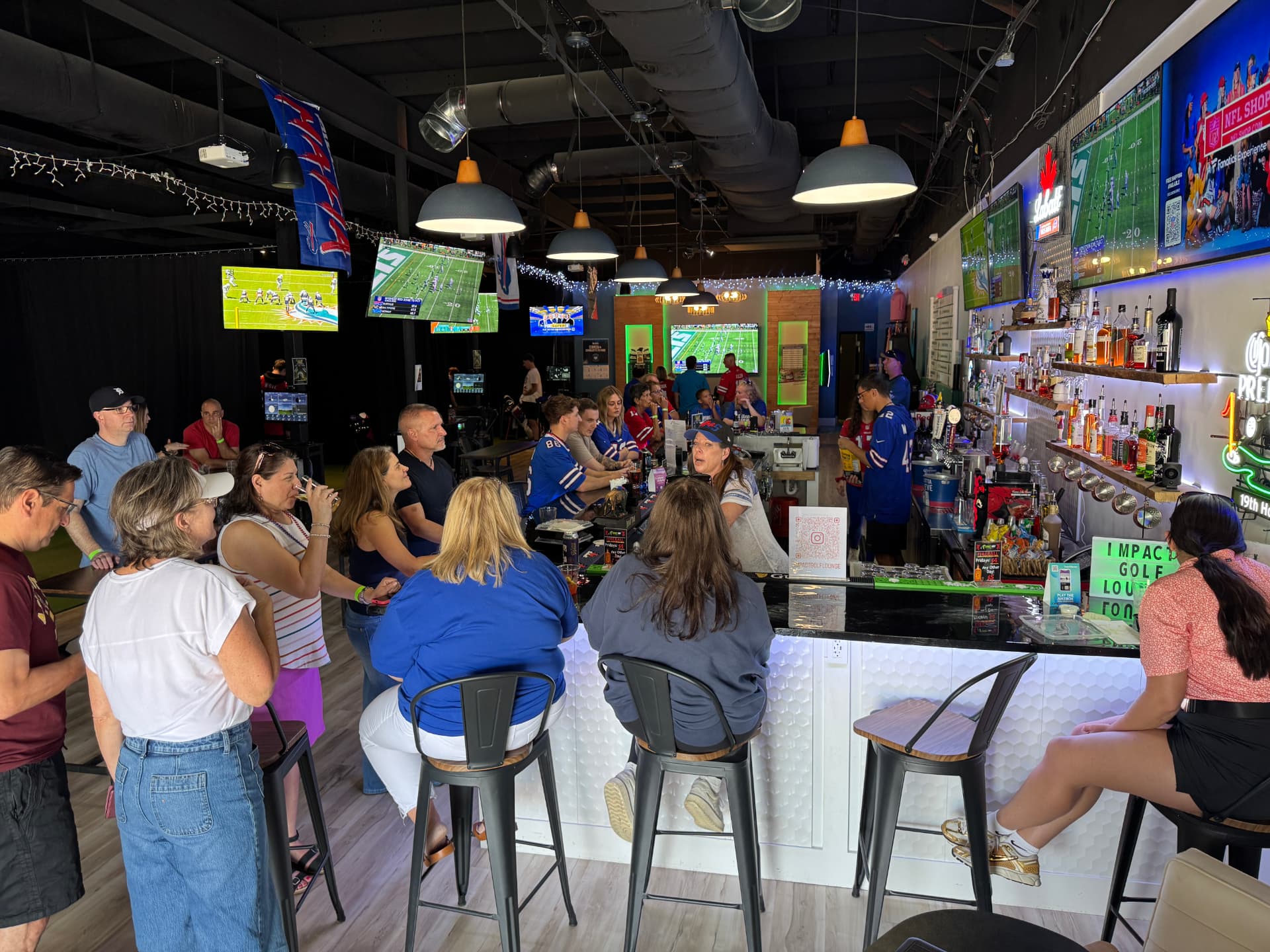 Guests at the bar watching football on the big screens at Impact Golf Lounge